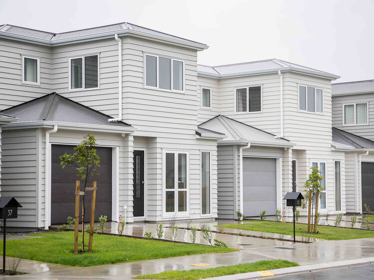Newly built row of modern white two-storey townhouses on a wet day.