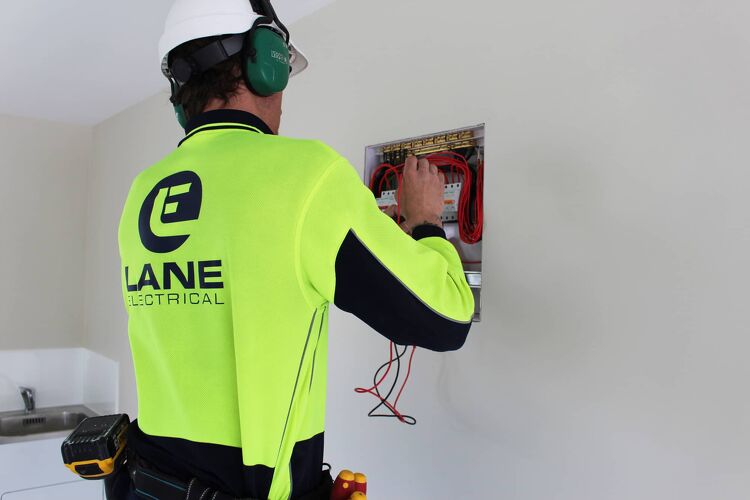 Lane Electrical worker inspecting a circuit board inside a residential property.