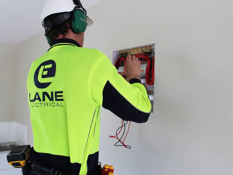 Lane Electrical worker inspecting a circuit board inside a residential property.