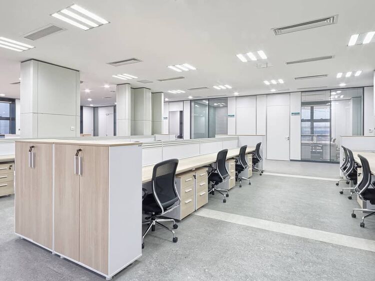 Modern open-plan office space with LED ceiling lights and cubicles.
