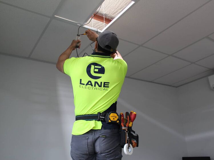 Lane Electrical technician wiring ceiling lighting in an office.