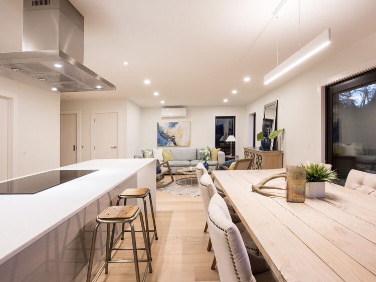 Open-plan kitchen, dining, and lounge area with ceiling spotlights.
