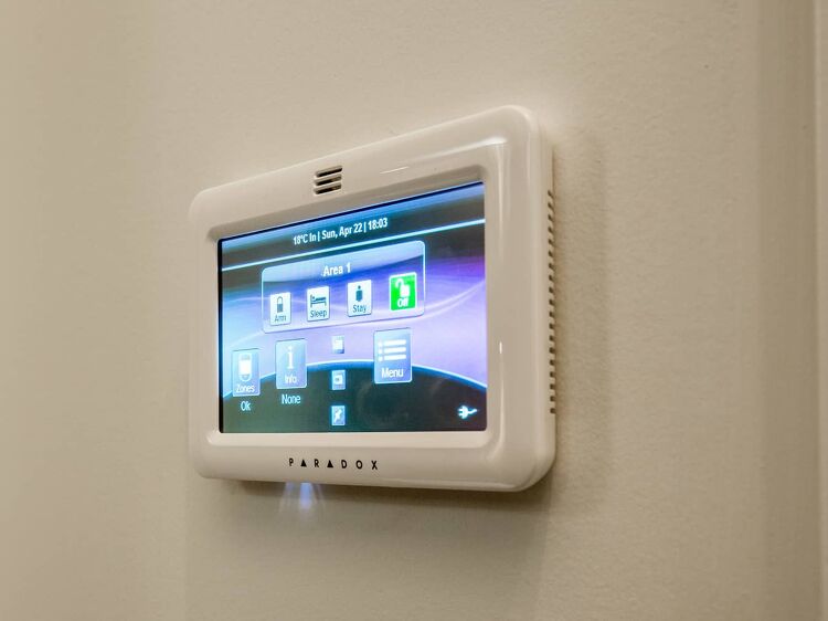 Wall-mounted home security system touchscreen panel by Paradox.